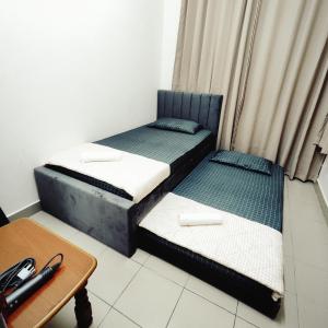 two twin beds in a room with a table at Cheras Landed Homestay 4BR - 10Pax - MRT Suntex in Cheras