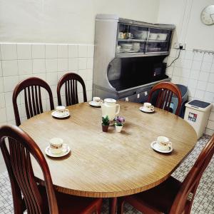 a wooden table in a kitchen with cups and saucers at Cheras Landed Homestay 4BR - 10Pax - MRT Suntex in Cheras