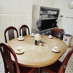 un tavolo di legno in una cucina con tazze e piattini di Cheras Landed Homestay 4BR - 10Pax - MRT Suntex a Cheras Altre 15 foto