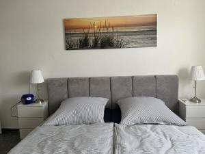 a bed with two pillows and a picture on the wall at NEU! Ferienwohnung Up de Warf in Dornum