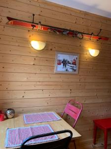 Una habitación con una pared de madera con una mesa y una silla rosa. en Studio Tiny en duplex - face télécabines, en Ax-les-Thermes 2 fotos más