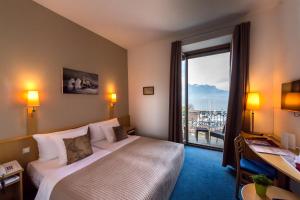 ein Hotelzimmer mit einem Bett und einem großen Fenster in der Unterkunft Hôtel Bon Rivage in Vevey