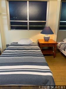 a bedroom with a bed and a lamp on a table at くぶむ荘 in Shimoyatori