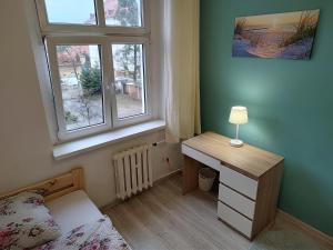a bedroom with a desk and a bed and a window at Magnolia rooms in Toruń