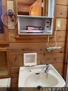 a bathroom with a sink and a tv on the wall at くぶむ荘 in Shimoyatori