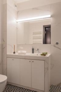 a white bathroom with a sink and a mirror at City Center Apartments Grano Residence in Gdańsk