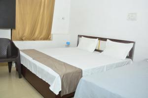 2 camas en una habitación de hotel con silla en Hotel Chandrasha Villa, en Ayodhya