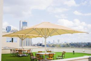 a group of tables and chairs under an umbrella on a roof at Capital M 2 Bedrooms Apartment- Deluxe Executive Rooms by BednBeyond Westlands Nairobi O72195O319 in Nairobi