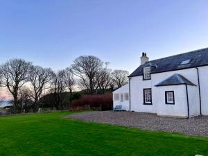 Biały dom z trawnikiem przed nim w obiekcie Rural Farmhouse on Kintyre, West Coast hidden gem w mieście Kildalloig