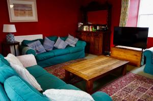 a living room with a green couch and a tv at Rural Farmhouse on Kintyre, West Coast hidden gem in Kildalloig