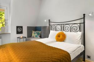 a bedroom with a bed with an orange pillow on it at Elite Apartments City Center Cosy Attic in Gdańsk
