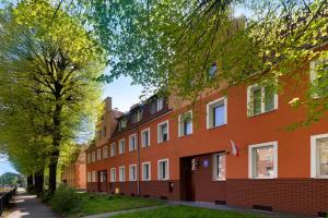 an orange building with trees in front of it at Elite Apartments City Center Cosy Attic in Gdańsk