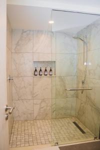 ナイロビにあるCapital M 2 Bedrooms by BednBeyond Westlands Nairobiのガラスドア付きのシャワー(ボトル3本付)