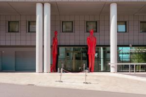 deux statues rouges devant un bâtiment dans l'établissement Ariha Hotel Cosenza, à Cosenza