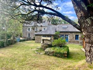 une vieille maison en pierre dans une cour avec un arbre dans l'établissement PENTY DU BELOU, cozy, en pleine campagne, 1 à 6 personnes, à Mellac