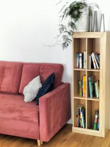 a red couch next to a book shelf with books at Kwatera Paprotka 23 in Warsaw