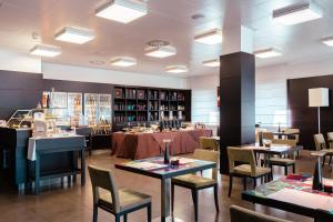 a dining room with tables and chairs and a bookstore at Ariha Hotel Cosenza in Cosenza