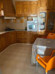 una cocina con armarios de madera y una mesa con sillas naranjas en Dar kouka, en Tataouine