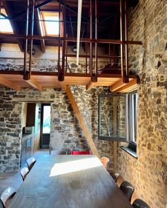 einen großen Holztisch in einem Zimmer mit einer Steinmauer in der Unterkunft Can Sau in Sant Joan de les Abadesses