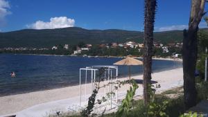 a beach with an umbrella and a body of water at Apartman Batarelo in Gornji Karin
