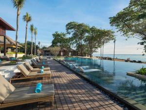 - une rangée de chaises longues à côté de la piscine dans l'établissement Novotel Bali Benoa, à Nusa Dua