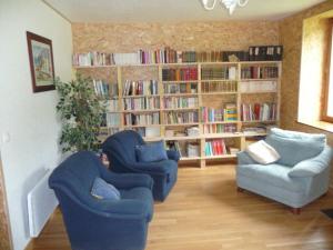 a living room with two chairs and a book shelf at Le Moulin Berthon in Vernusse