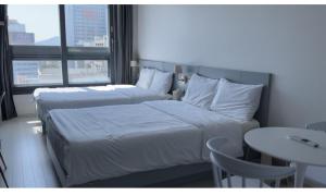 Cette chambre comprend deux lits, une table et une fenêtre. dans l'établissement Gurujam, à Daegu