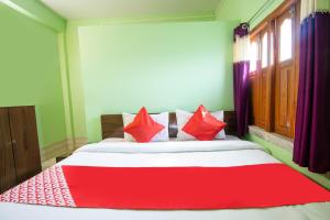 sypialnia z czerwono-białym łóżkiem z czerwonymi poduszkami w obiekcie OYO Hotel Taj International w mieście Baharampur