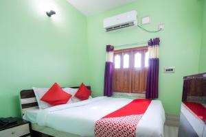 sypialnia z łóżkiem z czerwonymi poduszkami w obiekcie OYO Hotel Taj International w mieście Baharampur
