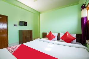 sypialnia z dużym białym łóżkiem z czerwonymi poduszkami w obiekcie OYO Hotel Taj International w mieście Baharampur