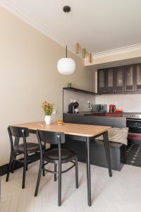 a kitchen with a wooden table and black chairs at City Center Apartments Grano Residence in Gdańsk