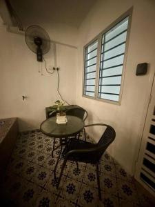 a room with a table and two chairs and a fan at Homestay Rumah Puteh Melaka in Kampong Bukit Katil