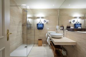 La salle de bains est pourvue d'un lavabo et d'une douche en verre. dans l'établissement Villa Favorita - Parkhotel Delta, à Ascona