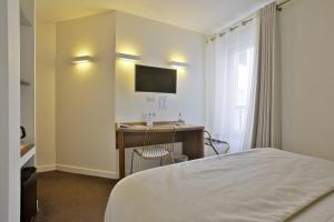 um quarto de hotel com uma cama e uma secretária com uma televisão em Hotel Le Relais Saint-Jacques em Saint-Jean-de-Luz