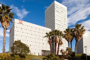 un gran edificio blanco con palmeras delante en Ibis Barcelona Santa Coloma, en Santa Coloma