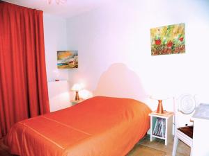 sypialnia z pomarańczowym łóżkiem i czerwoną zasłoną w obiekcie Les Malvaux w mieście Huriel