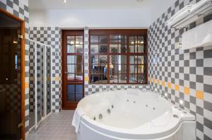 a large white tub in a bathroom with checkered tiles at Daugirdas Old City Hotel in Kaunas