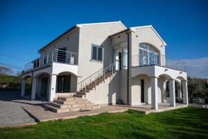 Edificio blanco con escaleras y balcón en Rez de maison neuve Piscine WiFi Poolhouse en Pierre, en Penta-di-Casinca