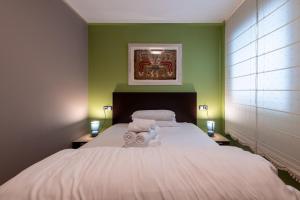 a bedroom with a large white bed with green walls at Apartamento moderno bh aspen atico con vistas in El Tarter