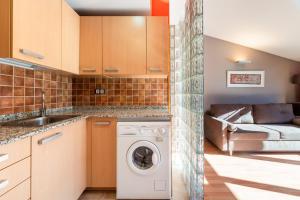 a kitchen with a washer and dryer and a couch at Apartamento moderno bh aspen atico con vistas in El Tarter