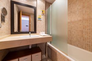 a bathroom with a sink and a mirror and a tub at Apartamento moderno bh aspen atico con vistas in El Tarter