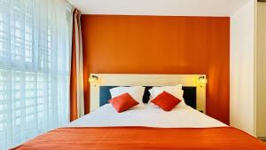 ボルドーにあるシティ レジデンス ボルドー サントルのベッドルーム1室(オレンジと白の枕が備わるベッド1台付)