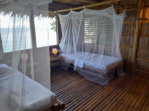 ein Schlafzimmer mit einem Bett und Moskitonetzen in einem Zimmer in der Unterkunft Kookoo's nest eco-lodge in Siaton