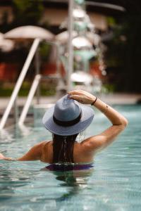 une femme portant un chapeau dans une piscine dans l'établissement DAS RONACHER Thermal Spa Hotel, à Bad Kleinkirchheim