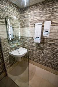 La salle de bains est pourvue d'un lavabo et d'une douche en verre. dans l'établissement Hôtel du Phare, à Kribi