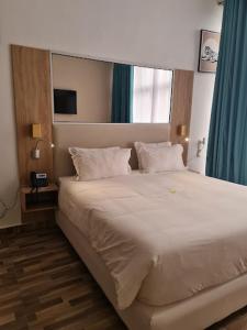 1 dormitorio con 1 cama blanca grande y ventana en Hôtel du Phare en Kribi