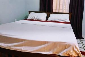uma cama grande com lençóis brancos e almofadas em shiks appartment em Malindi