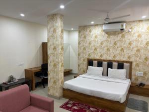 1 dormitorio con 1 cama y 1 silla rosa en Hotel ARRAJ, Raipur en Raipur