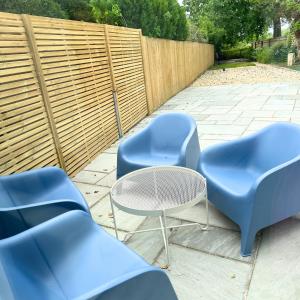 trois chaises bleues, une table et une clôture dans l'établissement Countryside 2 bed cottage- Aylesbury, à Haddenham