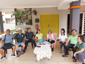 um grupo de pessoas sentadas à volta de uma mesa numa sala em Greenleaf Angsana Homestay em Jerantut